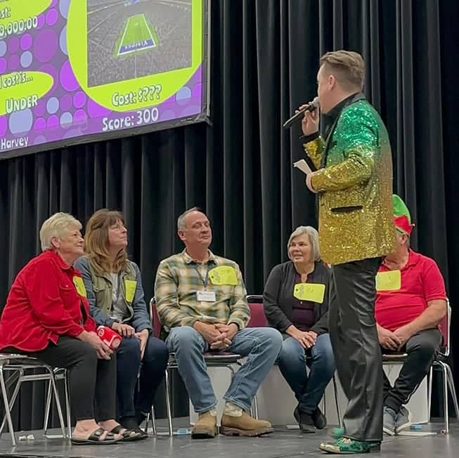 game show host on stage talking into microphone