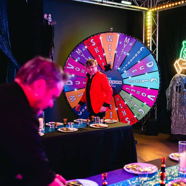 game show studio host in front of wheel