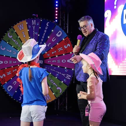 game show studio host asking kid contestants a question