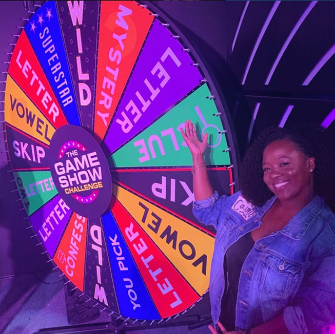 woman standing in front of wheel of fortune